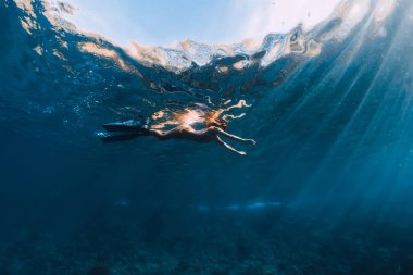 Mavi okyanusta yüzgeçlerle yüzen kadın. Sualtı görünümü