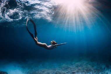 Kadın serbest dalgıç yüzgeçleri ile süzülür. kumlu deniz üzerinde. Serbest dalış ve