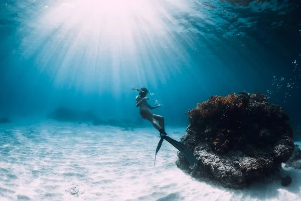 Plongeur libre jeune femme avec des nageoires nager sur fond sablonneux underwat — Photo