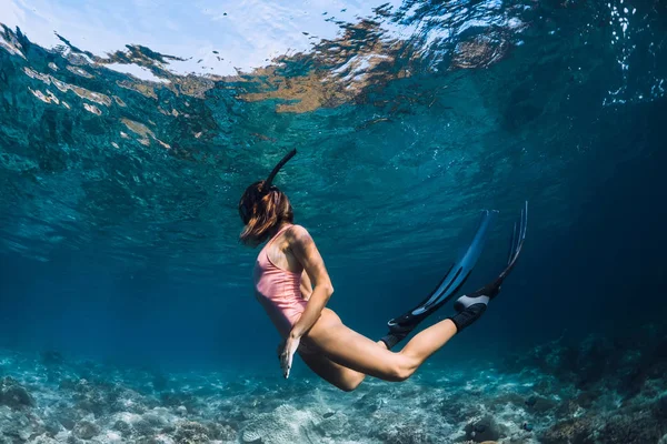 Freitaucherin schwimmt in rosa Badeanzug mit Flossen unter Wasser. frei — Stockfoto