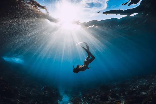 Donna subacquea libera con pinne sul fondo di corallo e sorprendente raggio di sole — Foto Stock