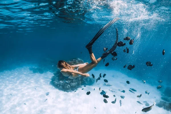 Mulher freediver desliza com barbatanas sobre o mar arenoso com peixes em H — Fotografia de Stock