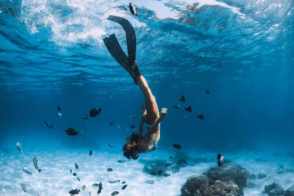 Freitaucherin mit Flossen über sandiges Meer mit Fischen — Stockfoto