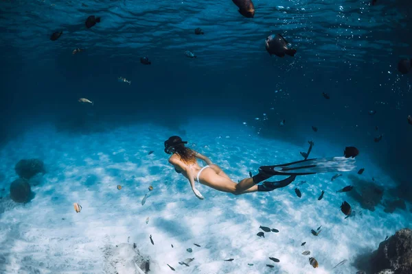 Freediver chica con aletas se desliza sobre fondo arenoso con peces en — Foto de Stock