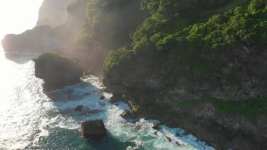 Kayalık uçurum, taşlar ve Bali güneş ışığı ile mavi okyanus. Havadan görünüm