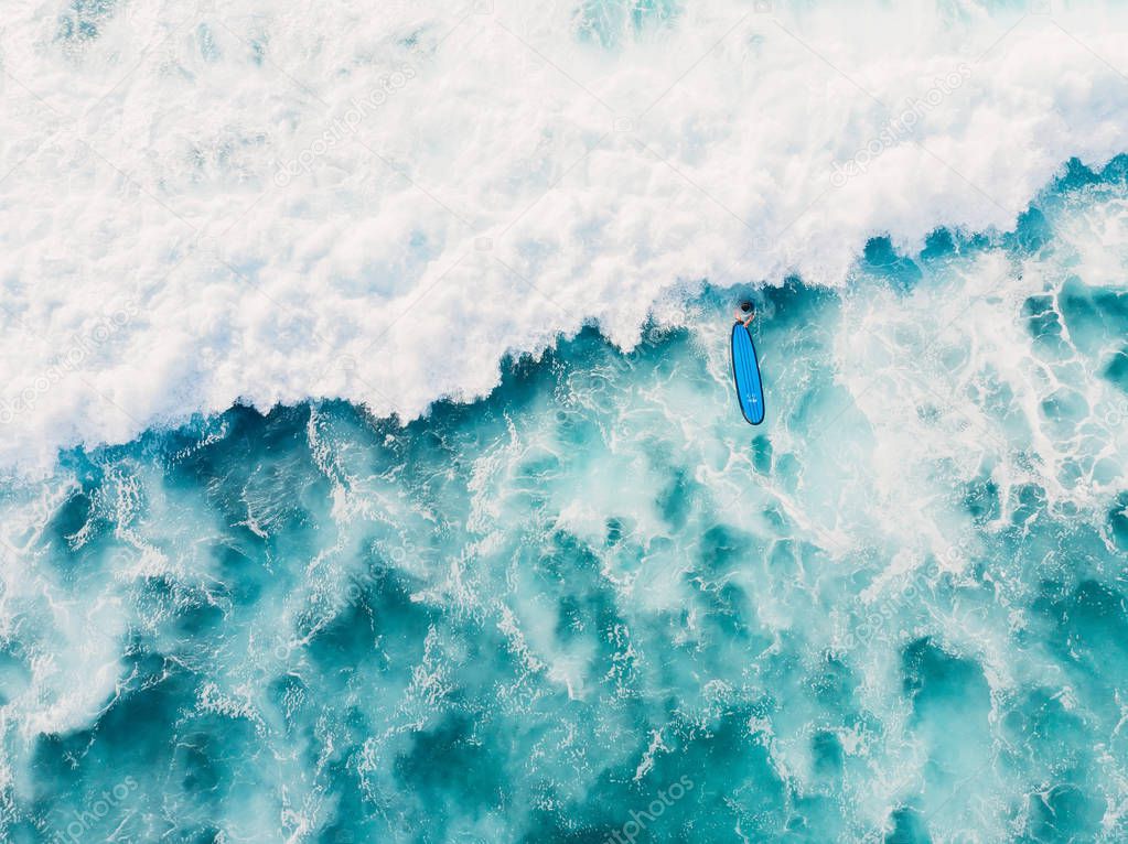 Aerial view of surfer and wave in ocean. Top view