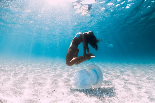 Woman diver glides over sandy sea with jellyfish. Freediving in — Stock Photo, Image