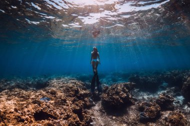 Yüzgeçli kadın serbest dalgıç denizde su altında süzülür