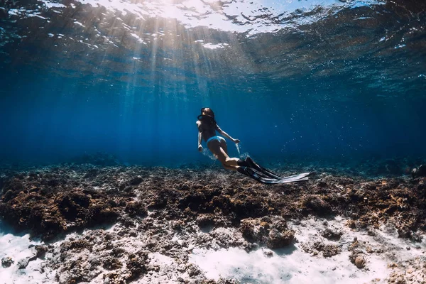 Mujer buzo libre con aletas se desliza sobre los corales en el mar azul . — Foto de Stock