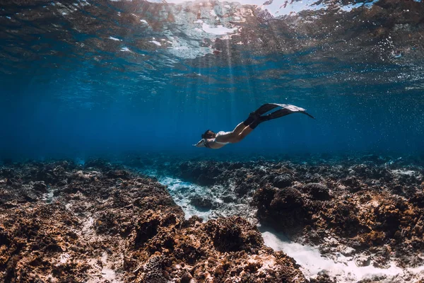 Mulher mergulhadora livre com barbatanas desliza sobre corais em mar azul . — Fotografia de Stock