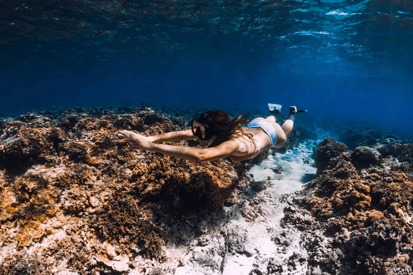 Mujer buzo libre con aletas se desliza sobre los corales en el mar azul . — Foto de Stock