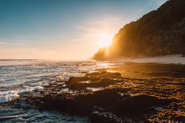 Пляж с океанскими волнами и солнечным светом на закате или на восходе солнца — стоковое фото