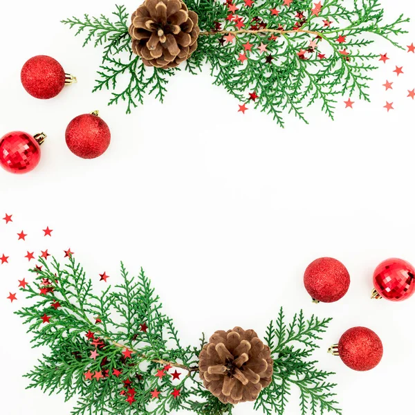 Christmas frame of pine branches and red decoration on white bac