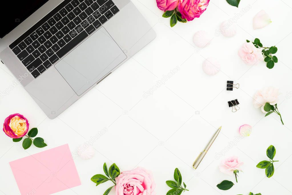 Laptop with pink flowers, pen, envelope and petals on white back