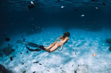 Yüzgeçleri ile Freediver kız balıklar ile kumlu alt üzerinde süzülür