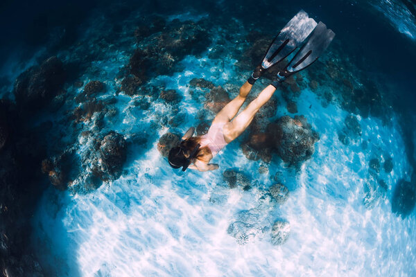 Slim woman freediver swim with fins underwater. Freediving in bl