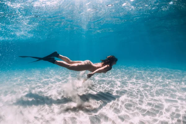 Freediver z płetwami ślizga się po piaszczystym morzu w przezroczystym oceanie. — Zdjęcie stockowe