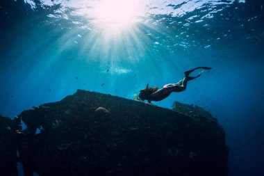 Yüzgeçleri suyun altında yüzen pembe mayo giyen serbest dalgıç kız.