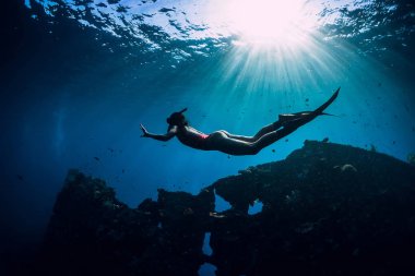 Yüzgeçleri suyun altında yüzen pembe mayo giyen serbest dalgıç kız.