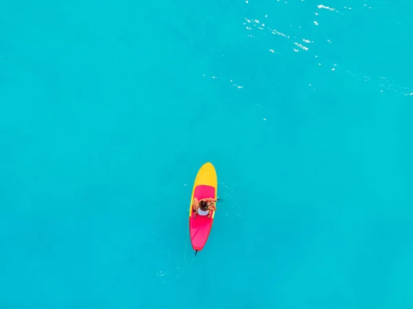 迷人的女人站在平静的蓝色海洋上的桨板上. — 图库照片