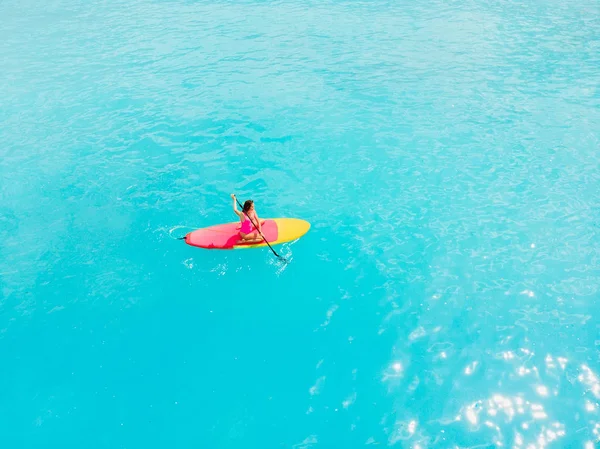 Atractiva mujer en stand up paddle board en un tranquilo océano azul . — Foto de Stock
