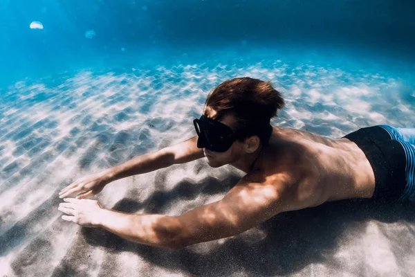 Freediver glijdt onder water over de zandbodem. Zwemmen met vin — Stockfoto