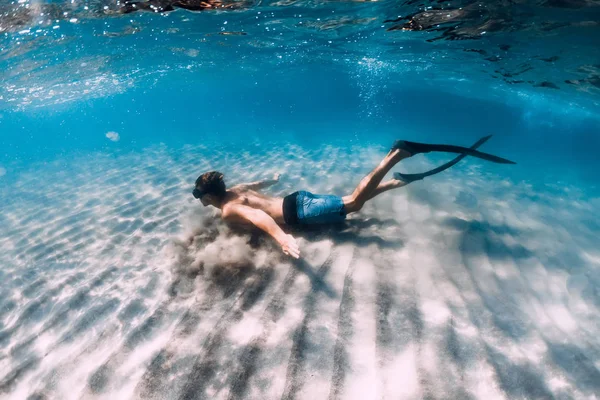 Freediver glijdt onder water over de zandbodem. Zwemmen met vin — Stockfoto