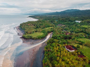 Nehir, okyanus ve dalgalı siyah kumsal manzarası