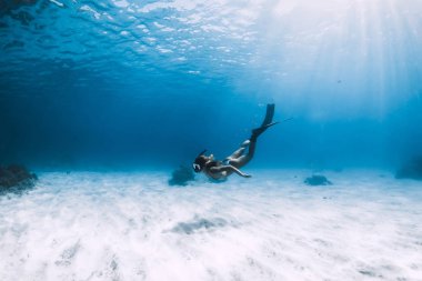 Çekici bir kadın serbest dalgıç kumlu denizin üzerinde yüzgeçleriyle süzülüyor. Ateş!