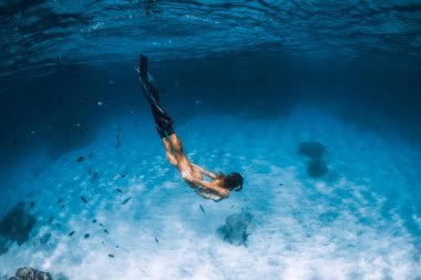 Bikinili genç kadın, kumlu denizde balıklarla süzülüyor. Hawaii 'de serbest dalış.