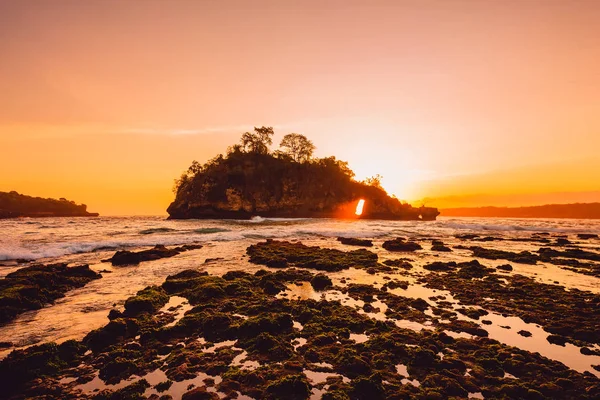 Ilha das rochas no oceano com o pôr do sol quente brilhante em Nusa Penida — Fotografia de Stock