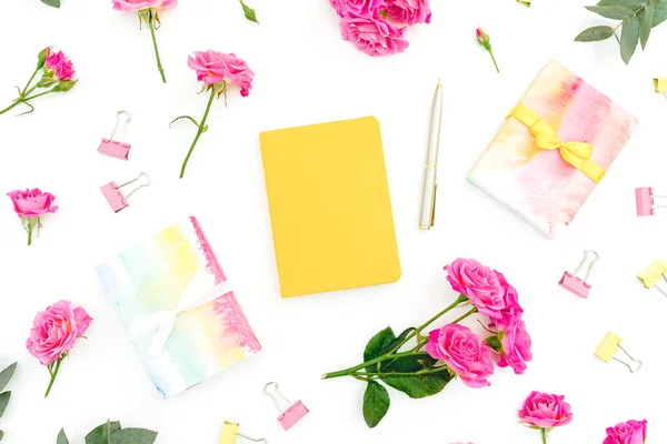 Female composition with notebook, gift and roses flowers on white background. Flat lay.