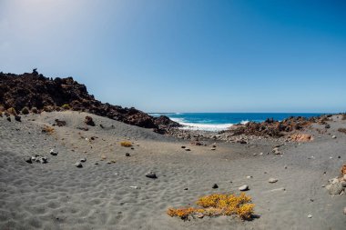 Volkanik kumlu plaj, taşlı ve okyanuslu kayalar Lanzarote, İspanya.