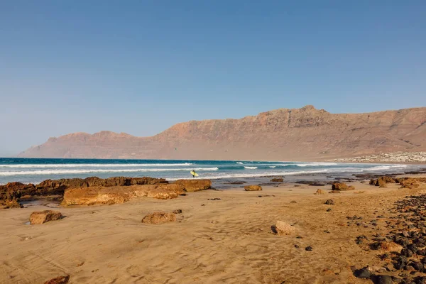 Famara beach, scenic landscape with ocean waves and mountains in Lanzarote, Canary islands