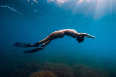 Yüzgeçleri olan sportif kadın, mavi okyanusta süzülüyor..