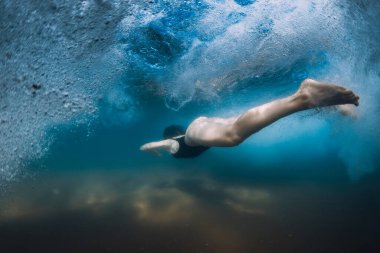 Okyanus dalgası altında sörf tahtası olmayan bir kadın. Sualtı ördeği daldı dalgaların ve kumlu zeminin altında