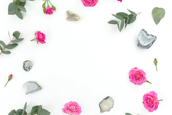 Floral frame with eucalyptus, roses flowers and Agate stones on white background. Flat lay