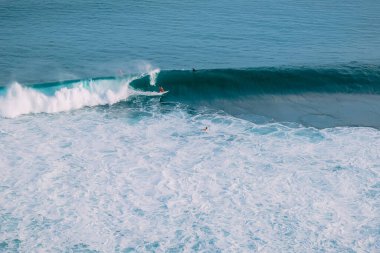 Sörfçülerle hava manzarası ve tropik okyanusta dalgalar.