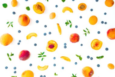 Beyaz arka planda yaban mersinli ve naneli şeftaliler. Yaz meyveleri. Üst Manzara. Düz yatıyordu