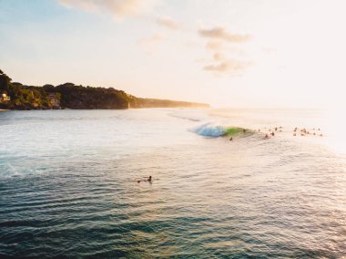 Dalgalar, sörfçüler ve günbatımı ışıklarıyla okyanus manzarası. Bali 'de Drone görünümü