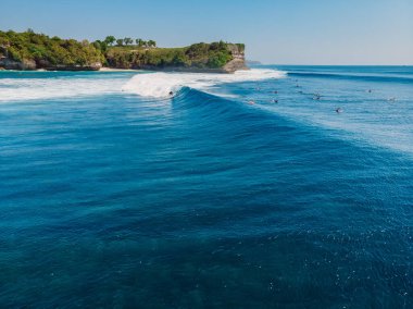 Mavi okyanusta sörf dalgaları ve arka planda uçurum. Dalgalı tropik adanın havadan görünüşü