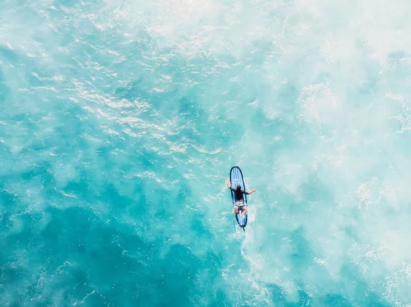 在蓝色的海洋中 冲浪运动员在冲浪板上划船的空中照片 顶部视图 — 图库照片