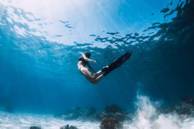 Kumlu zeminde yüzgeçleriyle poz veren özgür bir kadın. Hawaii adalarında mavi okyanusta serbest dalış