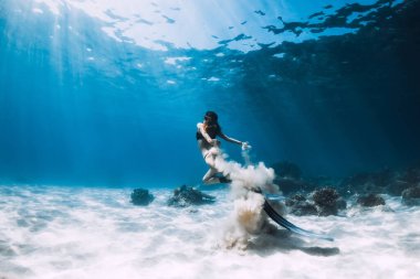 Kumlu zeminde yüzgeçleriyle poz veren özgür bir kadın. Hawaii adalarında mavi okyanusta serbest dalış