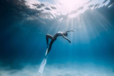 Freediver beyaz yüzgeçlerle kumlu denizde süzülür. Mavi okyanusta çekici bir serbest dalgıç.