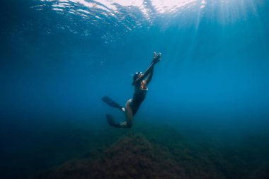 Serbest dalgıç, yüzgeçleriyle denizin altında süzülür. Kadın denizde serbest dalış yapıyor.