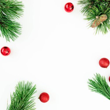 Noel ağacı dalları ve kırmızı toplar beyaz arka planda konfeti ile süslenmiş. Düz yatış, üst görünüm