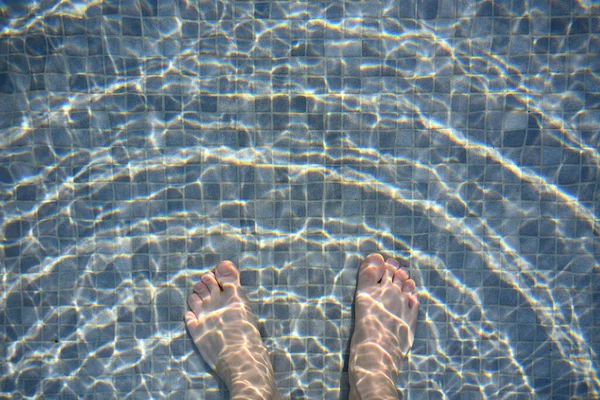 プールの白い男の足 混合暗いと薄い灰色のモザイクの床混合水の表面の波は黄金の太陽の下でジャンプします — ストック写真