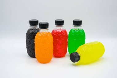 Beyaz arka planda sıralanmış çeşitli renklerde plastik su şişeleri.