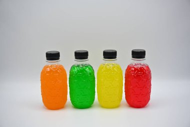 Beyaz arka planda sıralanmış çeşitli renklerde plastik su şişeleri.